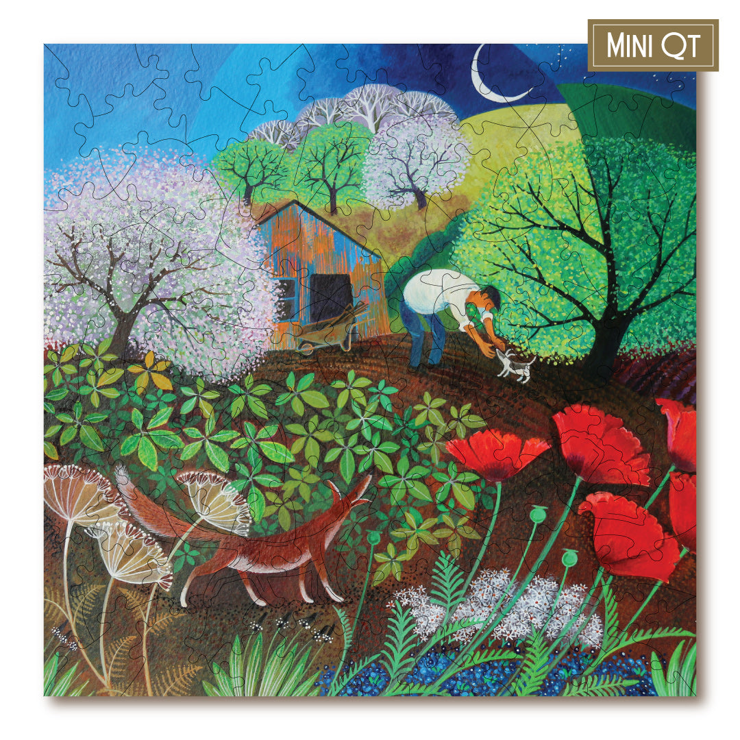 A completed jigsaw puzzle featuring a colorful folk-art style scene with a person tending a small dog in a garden, surrounded by blooming trees, flowers, a fox, and a small house under a crescent moon. A small label in the top-right corner reads MINI QT.